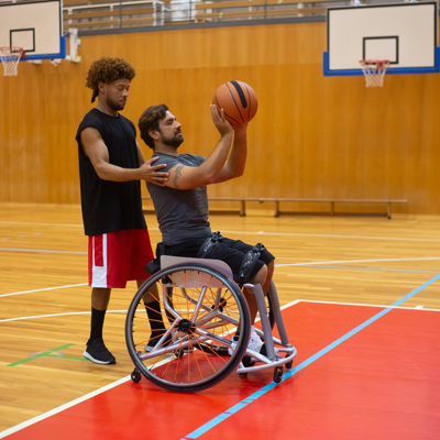 a guardian helping his disabled ward play basketball